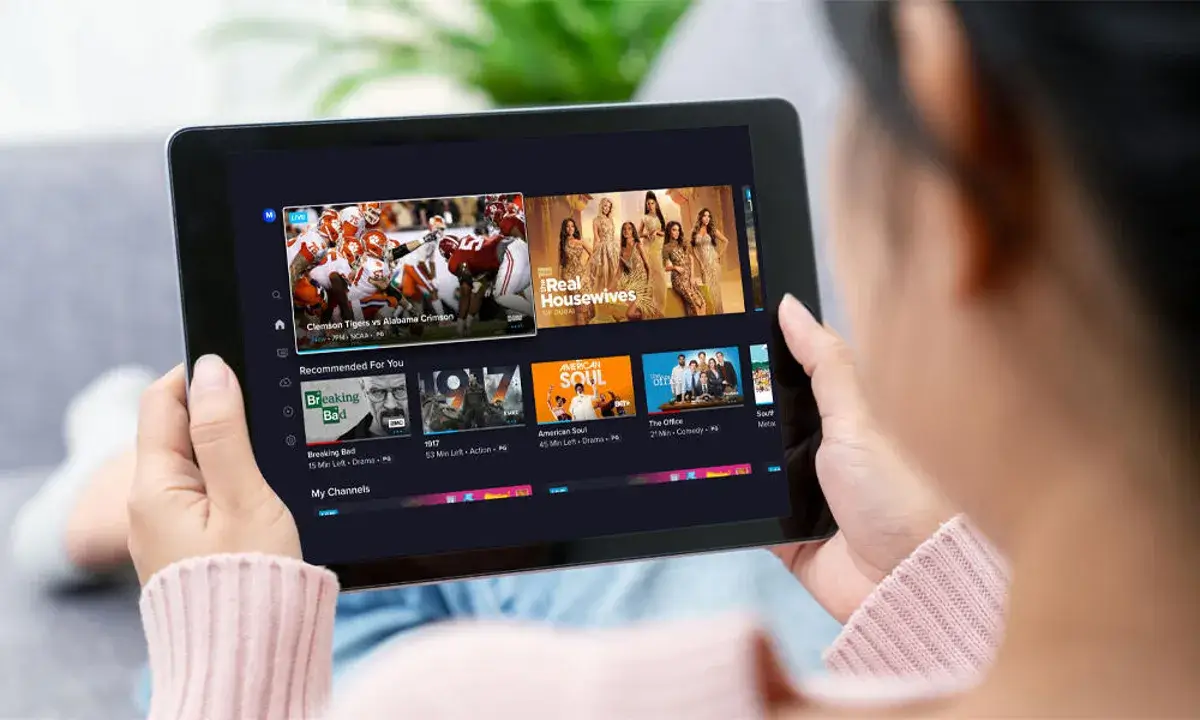 Person watching IPTV UK service on tablet showing live sports and entertainment channels with IPVision UK streaming platform